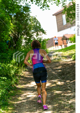 Rear view on active young woman running during the triathlon competition. 116913334