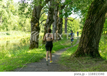 Rear view on active young woman running during the triathlon competition. Rear view on active young woman running during the triathlon competition. 116913340