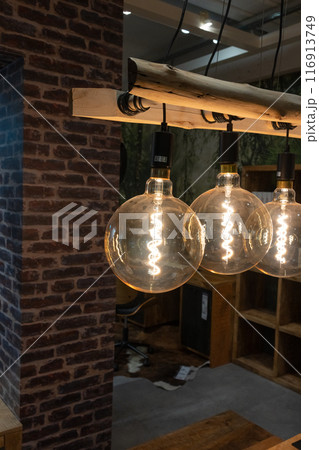 Decorative incandescent bulbs in Edison style on a brick wall background. Decorative incandescent bulbs in Edison style on a brick wall background. 116913749