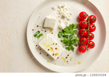 feta cheese, for salads, with cherry , green butter, greens, on a white plate, appetizer, top view, close-up, feta cheese, for salads, with cherry , green butter, greens, on a white plate, appetizer, top view, close-up, 116914104