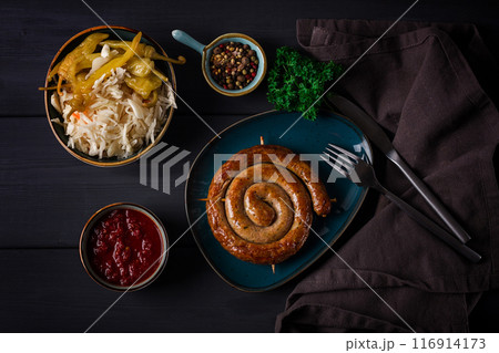 Traditional German dish, Fried spiral sausage, with sauerkraut,with red sauce, on a dark gray wooden background, top view, horizontal, no people, Traditional German dish, Fried spiral sausage, with sauerkraut,with red sauce, on a dark gray wooden background, top view, horizontal, no people, 116914173