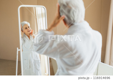 Love yourself. Beautiful old woman enjoying mirror reflection. Senior older lady spending morning in bathroom looking at mirror confident happy. Woman doing daily morning beauty routine. Self love 116914696