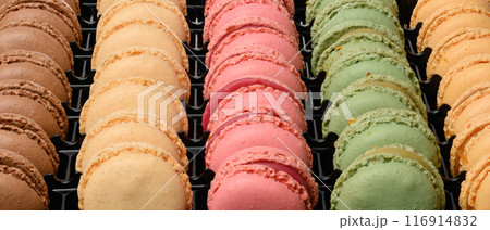 Multi-colored macarons in a plastic box, top view. 116914832