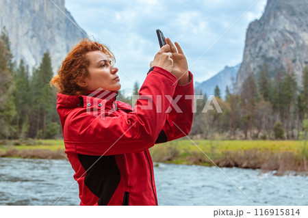 Woman in a red jacket takes photographs of nature 116915814