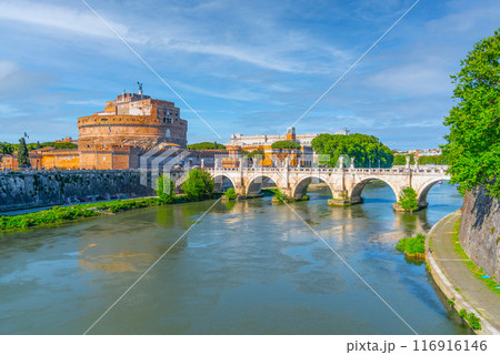 Brilliant sunshine bathes Castel Sant Angelo and the ancient Ponte Sant Angelo bridge over the Tiber River, highlighting Romes enduring architectural marvels. Rome, Italy 116916146