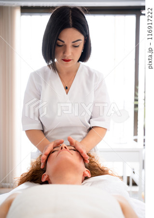 Masseur massaging relaxed woman lying on bed in Masseur massaging relaxed woman lying on bed in 116917222