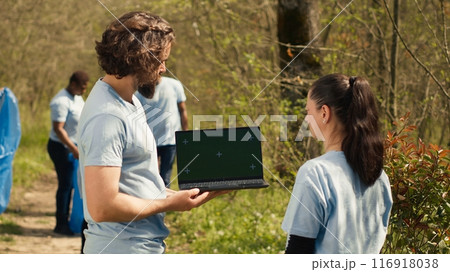 Team of climate and nature activists using laptop with greenscreen near a forest, volunteering to pick up trash and plant trees for future generations. Environmental protection. Camera A. Team of climate and nature activists using laptop with greenscreen near a forest, volunteering to pick up trash and plant trees for future generations. Environmental protection. Camera A. 116918038
