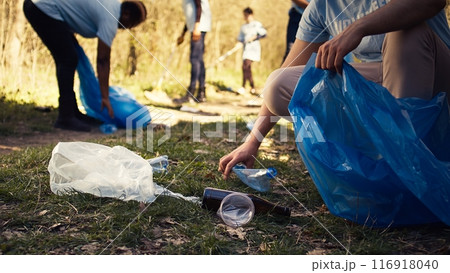 People using proper tools to clean the forest and recycle plastic waste, fighting pollution and illegal dumping. Activists volunteering to collect rubbish from the woods. Close up. Camera B. 116918040
