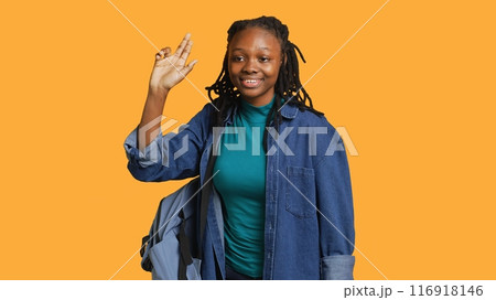 Enthusiastic african american student raising hand up to answer question, excited to tell teacher explanation to question in class, isolated over studio background, camera A Enthusiastic african american student raising hand up to answer question, excited to tell teacher explanation to question in class, isolated over studio background, camera A 116918146
