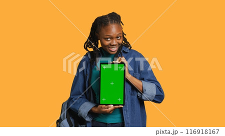 Smiling african american woman presenting tablet with green screen display, isolated over studio background. Cheerful BIPOC person creating promotion with chroma key device, camera A Smiling african american woman presenting tablet with green screen display, isolated over studio background. Cheerful BIPOC person creating promotion with chroma key device, camera A 116918167