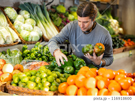 Portrait of satisfied man buying fresh bell peppers in grocery shop Portrait of satisfied man buying fresh bell peppers in grocery shop 116918600