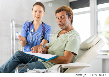 Patient signing informed consent form during medical consultation with female doctor 116918613