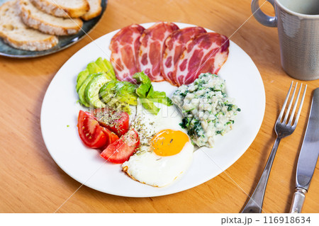 American breakfast includes fried egg,pork bacon,tomato slices and avocado,supplemented with bread American breakfast includes fried egg,pork bacon,tomato slices and avocado,supplemented with bread 116918634