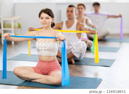 Young girl doing arm workout with band sitting cross-legged 116918651