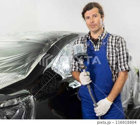 Repairman painter hand in protective glove with airbrush pulverizer painting car body 116918804
