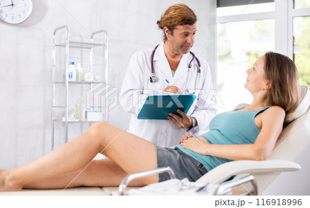 Adult male doctor signing contract with female patient Adult male doctor signing contract with female patient 116918996