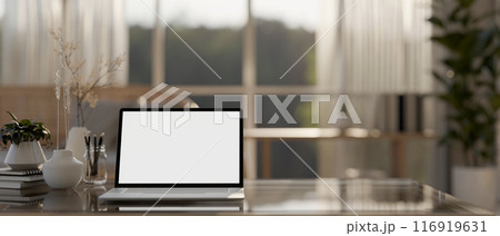 A laptop computer with a white-screen mockup and decor on a table in a cozy Scandinavian living room 116919631