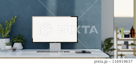 A PC computer with a white-screen mockup on a white table against the blue wall in a modern room. 116919637