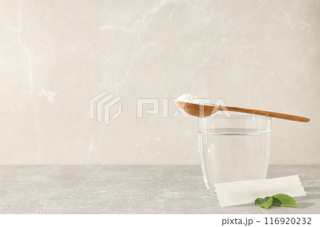 Collagen powder in a wooden spoon with a glass of water Collagen powder in a wooden spoon with a glass of water 116920232