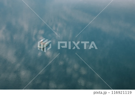 A breathtaking aerial view showcases a small boat sailing peacefully on calm and serene waters 116921119