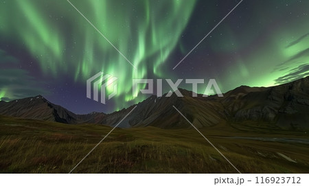 A remote mountain landscape under a clear night sky, lit by the northern lights ethereal glow. 116923712