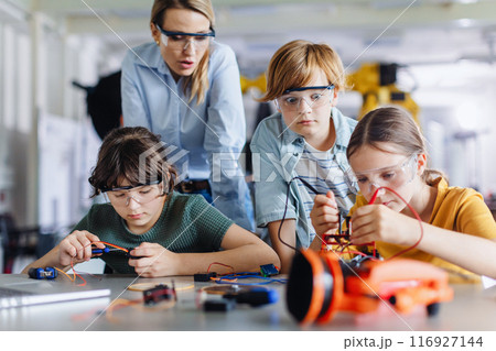 Children learning robotics in Elementary school. Young students building robot in after school robotics club. Children learning robotics in Elementary school. Young students building robot in after school robotics club. 116927144