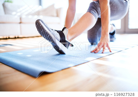 Woman's home fitness routine. Close up on legs, workout on gym mat in living room, sporty woman wearing sportswear. 116927328
