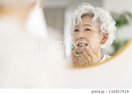 鏡を見ながら歯茎を気にするシニア女性 116927419