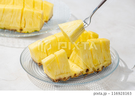 カットしたパイナップルをフォークでさして食べる 116928163
