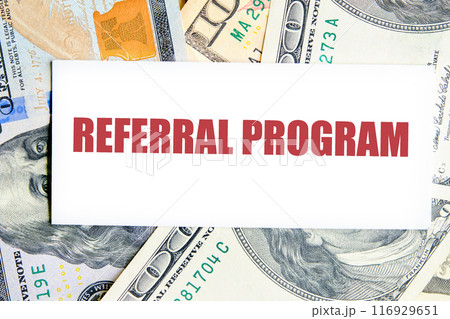 REFERRAL PROGRAM word. text written on a business card against the background of dollar bills 116929651
