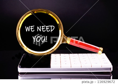 Text WE NEED YOU through a magnifying glass on a calculator on a black background Text WE NEED YOU through a magnifying glass on a calculator on a black background 116929672