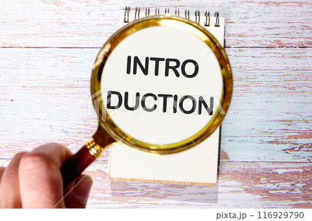 Introduction Word for business concept. INTRODUCTION written in a white notebook on old boards through a magnifying glass in a man's hand 116929790
