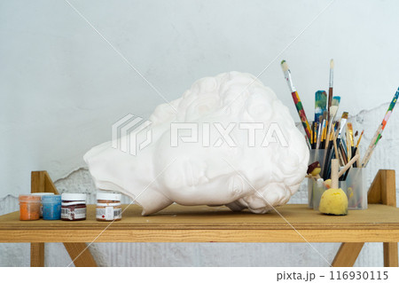 An Artistic Workspace that showcases a Bust along with a range of Painting Supplies for creative expression 116930115