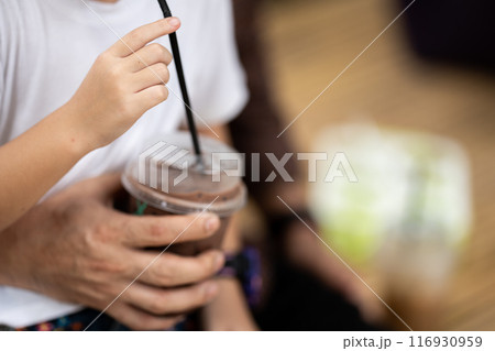 Chocolate milk is being held and drunk by a girl that wearing white shirt. Chocolate milk is being held and drunk by a girl that wearing white shirt. 116930959