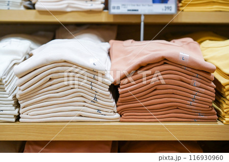 A pile of shirts, earth tone color, cream and brown was folded and put on shelf in cloth shop department store. A pile of shirts, earth tone color, cream and brown was folded and put on shelf in cloth shop department store. 116930960