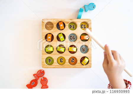 Topview, flatlay of Kid's hands are playing and finding the matched number in the wooden magnetic fishing game, 116930993
