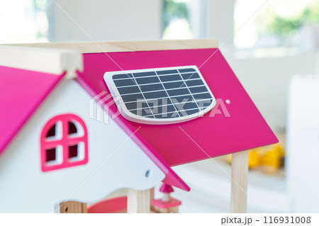 A solar cell is installed on the pink roof of a model wooden toy house. A solar cell is installed on the pink roof of a model wooden toy house. 116931008