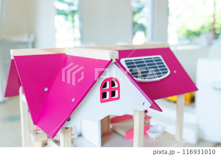 A solar cell is installed on the pink roof of a model wooden toy house. 116931010