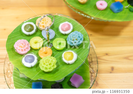 Varieties traditional colorful Thai desserts set; NamDokMai (steaming flour), PiekPoon (black custard), LeumKluen (coconut custard & steaming bean), KanomChan (layer pudding cake) 116931350