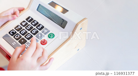 Kids are playing a wooden toy cash register by pressing the number seven, and others on it, respectively. Kids are playing a wooden toy cash register by pressing the number seven, and others on it, respectively. 116931377
