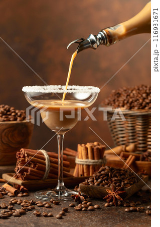 Chocolate martini cocktail or cream liquor is poured from a bottle into a glass. Chocolate martini cocktail or cream liquor is poured from a bottle into a glass. 116931671