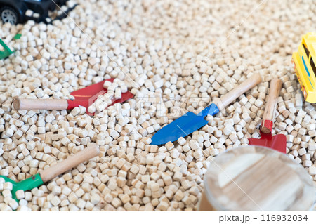 Yellow construction toy vehicles and Dinosaurs Toys are placed in kids playground filled with wooden cubes around it. Yellow construction toy vehicles and Dinosaurs Toys are placed in kids playground filled with wooden cubes around it. 116932034