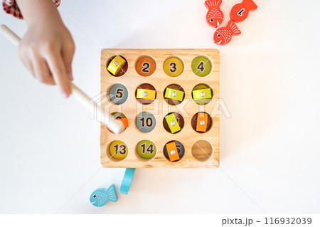 Topview, flatlay of Kid's hands are playing and finding the matched number in the wooden magnetic fishing game, Topview, flatlay of Kid's hands are playing and finding the matched number in the wooden magnetic fishing game, 116932039