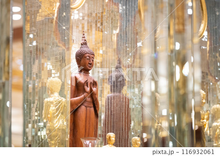 standing Buddha statue made of wood was placed between the smaller golden Buddha images of apostles. 116932061