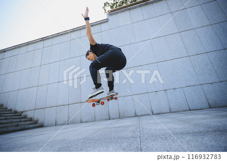 Asian woman skateboarder skateboarding in modern city Asian woman skateboarder skateboarding in modern city 116932783
