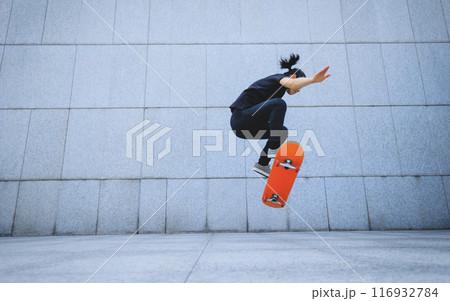 Asian woman skateboarder skateboarding in modern city Asian woman skateboarder skateboarding in modern city 116932784