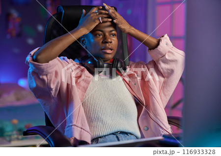 Portrait of frustrated African American woman watching videos or gaming at night at home Portrait of frustrated African American woman watching videos or gaming at night at home 116933328