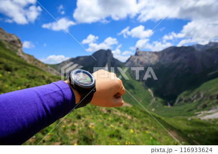 Hiker on high altitude mountain top checking the altimeter on the sports watch 116933624