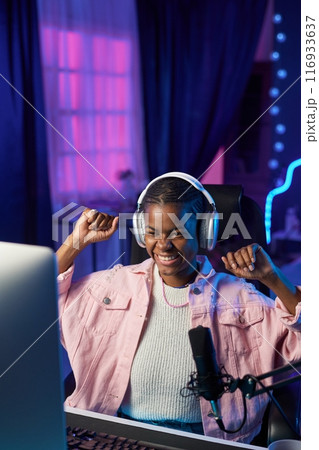 Vertical portrait of excited girl gamer cheering and celebrating victory while playing videogames at home copy space Vertical portrait of excited girl gamer cheering and celebrating victory while playing videogames at home copy space 116933637