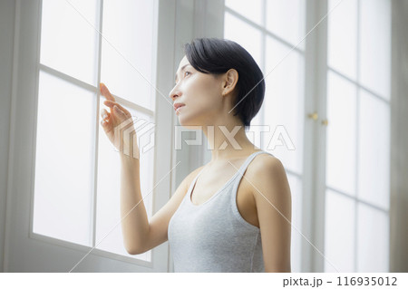 リビングで鏡を見るミドルの女性　 116935012